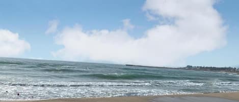 A beach with large rocks in the foreground and waves in the background.