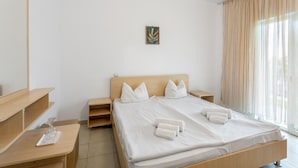 A hotel room with a large bed, a bedside table, a nightstand, a mirror, and a window with curtains. - Vraja Marii Eforie Nord (Eforie)