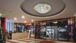 Un hall d’hôtel avec un motif de sol en forme d’étoile, un comptoir d’accueil et un luminaire au plafond.