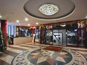 A hotel lobby with a star-shaped floor design, a reception desk, and a ceiling light fixture. - Apartments Flora (Samokov)