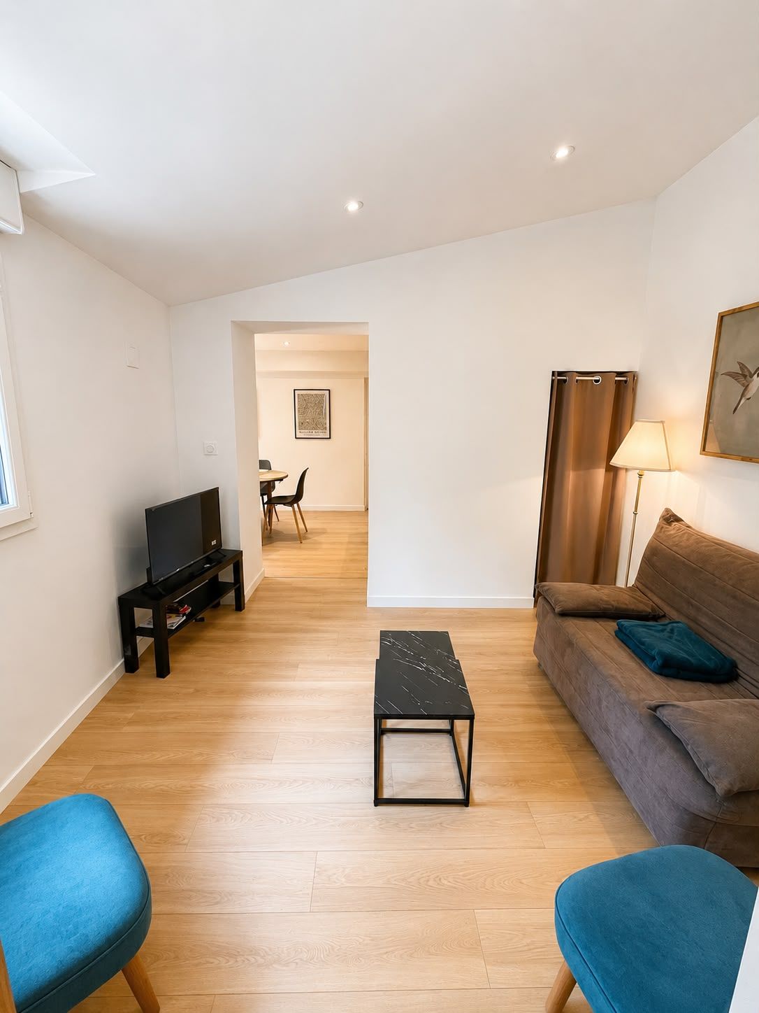 Un salon moderne avec un téléviseur à écran plat, un canapé, une table basse et une lampe.