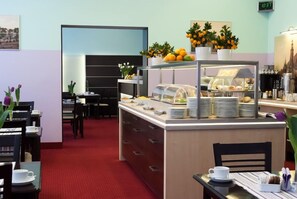 A breakfast area with a buffet counter, dining tables, and chairs. - Centrum Dikul (Wroclaw)