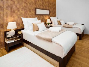 A hotel room with two beds, a nightstand with a lamp, a bedside table with a cup and papers, and a patterned wall. - Centrum Dikul (Wroclaw)