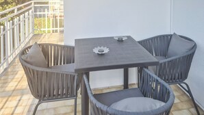Um pequeno pátio externo com uma mesa e quatro cadeiras.