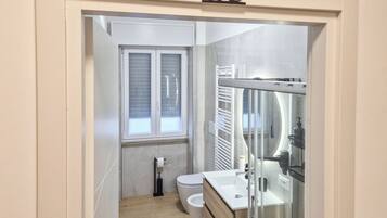 Un baño moderno con inodoro, lavamanos y cabina de ducha de vidrio.