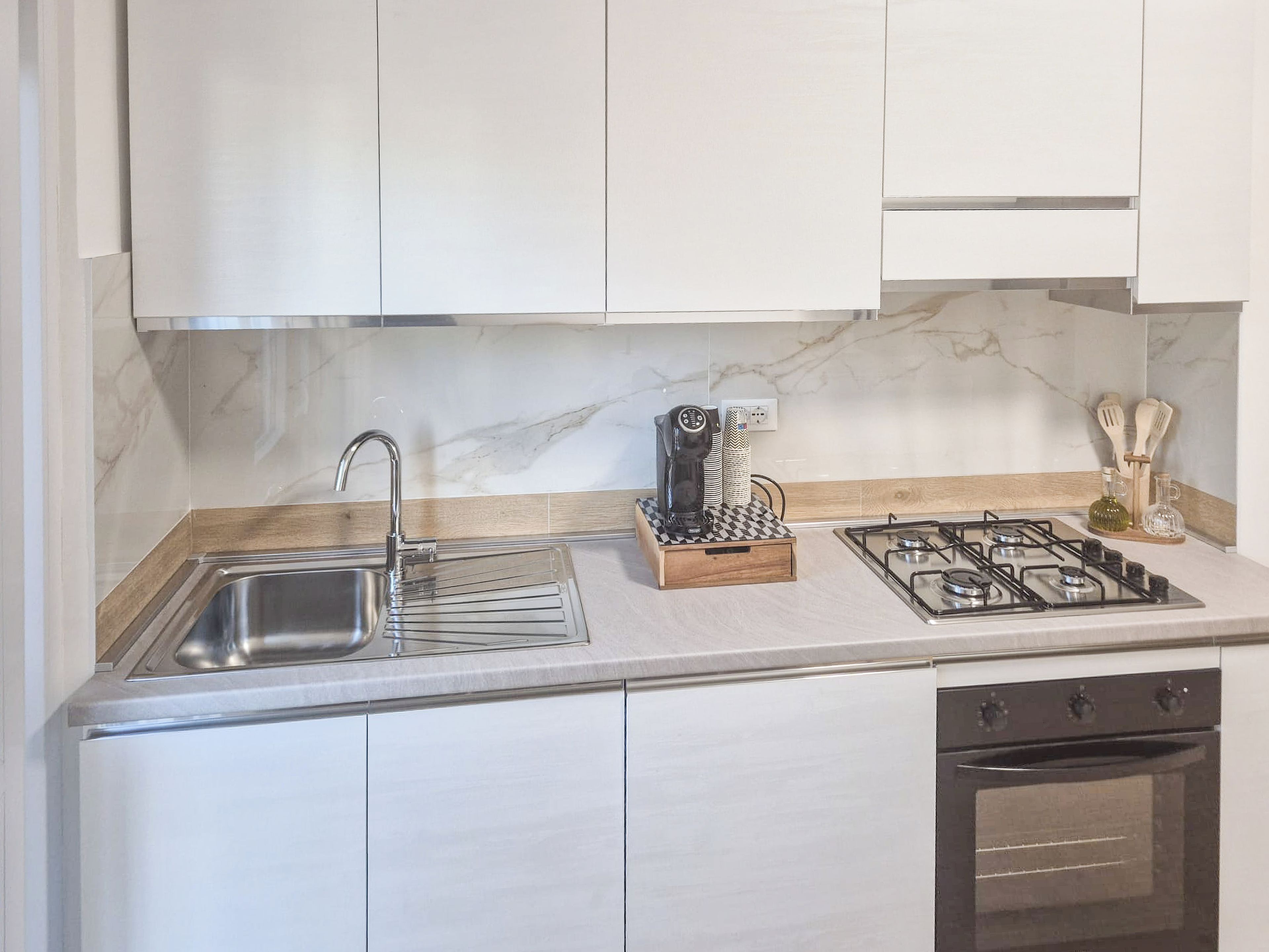 Una cocina moderna con un lavamanos de acero inoxidable, una estufa a gas y un horno empotrado.