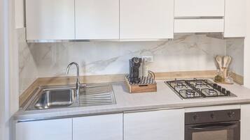 Una cocina moderna con un lavamanos de acero inoxidable, una estufa a gas y un horno empotrado.