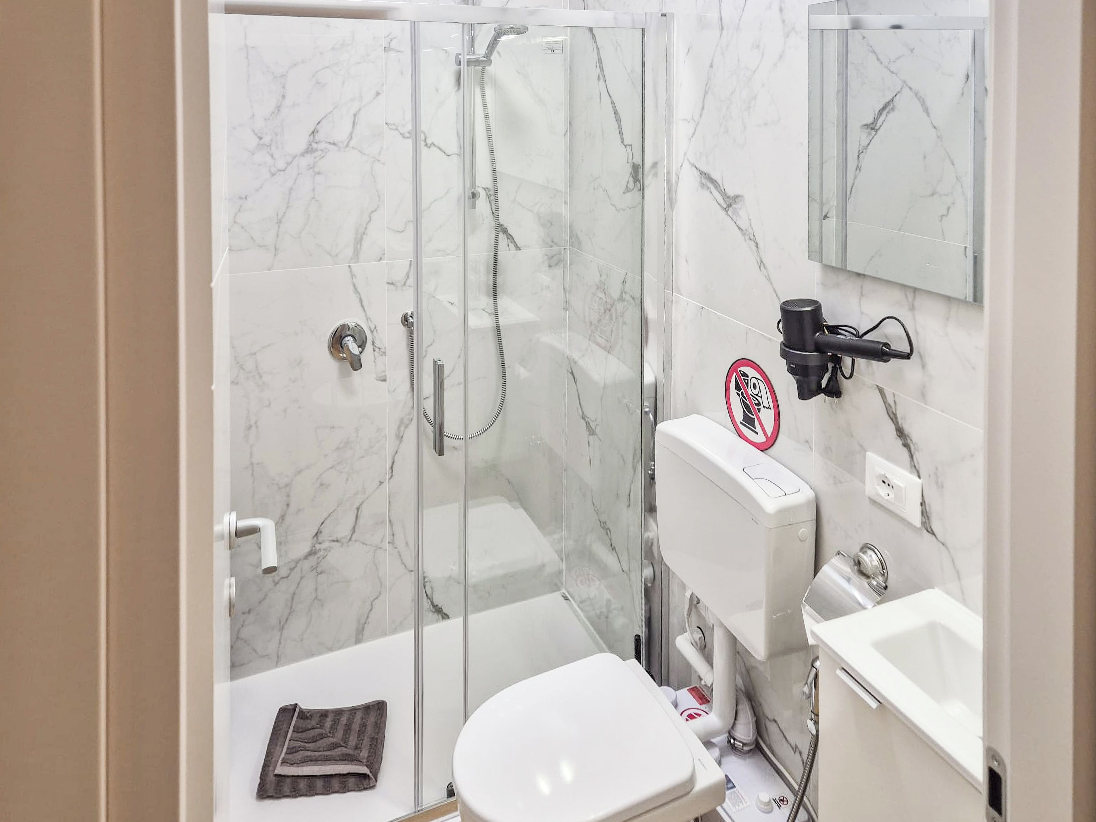 Un bagno con cabina doccia in vetro, un water e un lavandino.