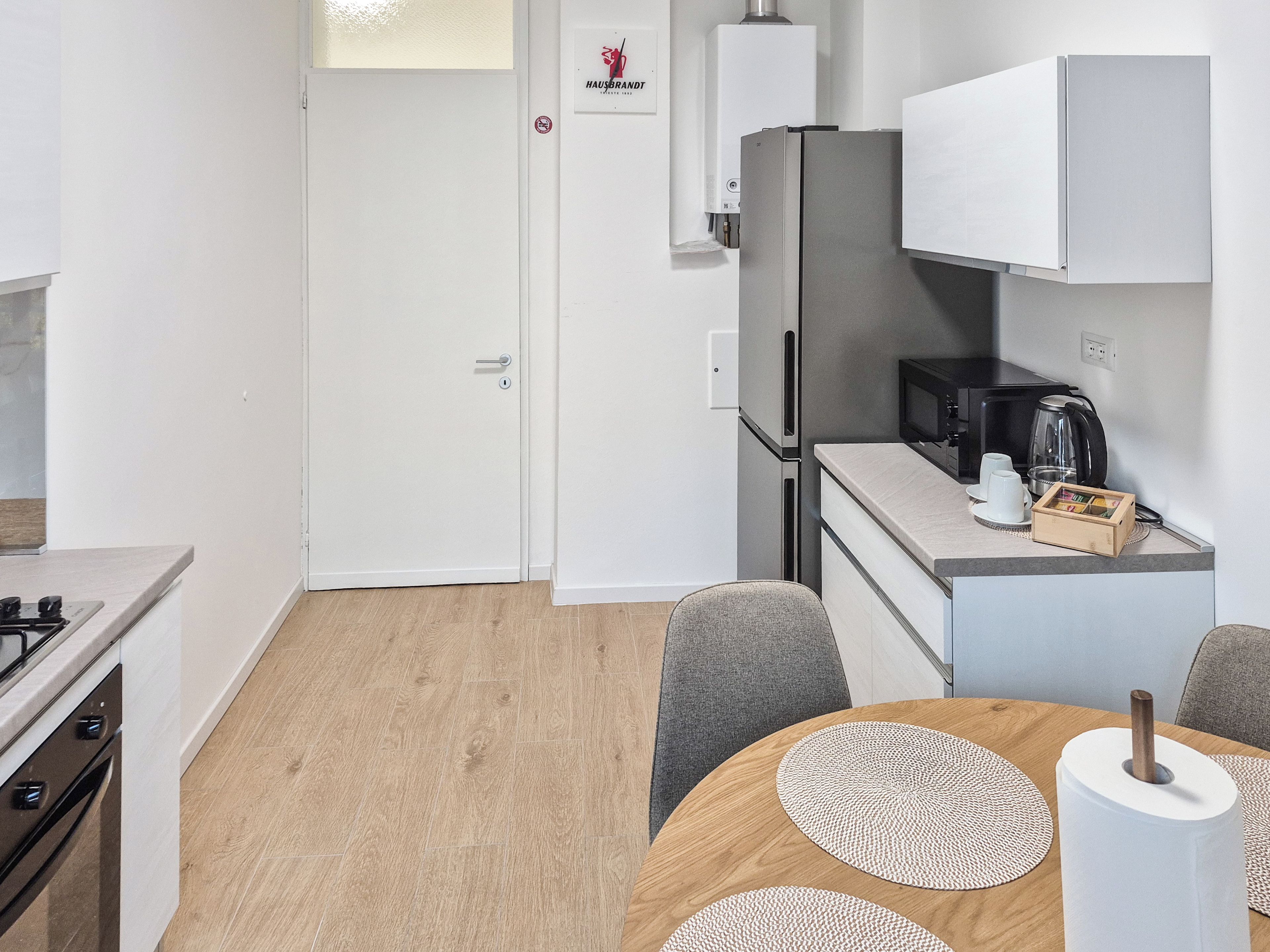 A modern kitchen with a refrigerator, microwave, and coffee maker.