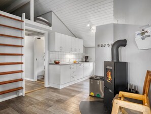 A modern kitchen with white cabinets, a built-in stove, and a wooden chair. - "Nandolf" - 200m to the fjord by Interhome (Vestervig)