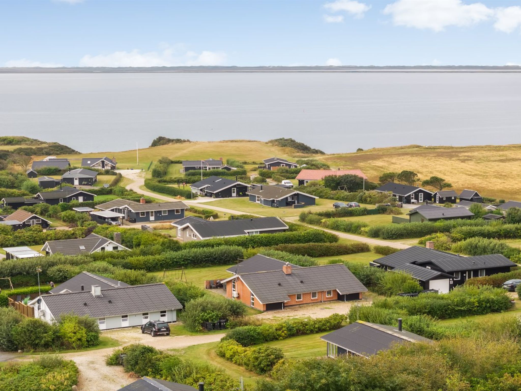 A coastal residential area with houses, a road, and a body of water.