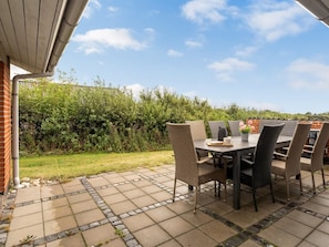 An outdoor patio with a table and chairs, surrounded by a hedge and a clear sky. - "Nandolf" - 200m to the fjord by Interhome (Vestervig)