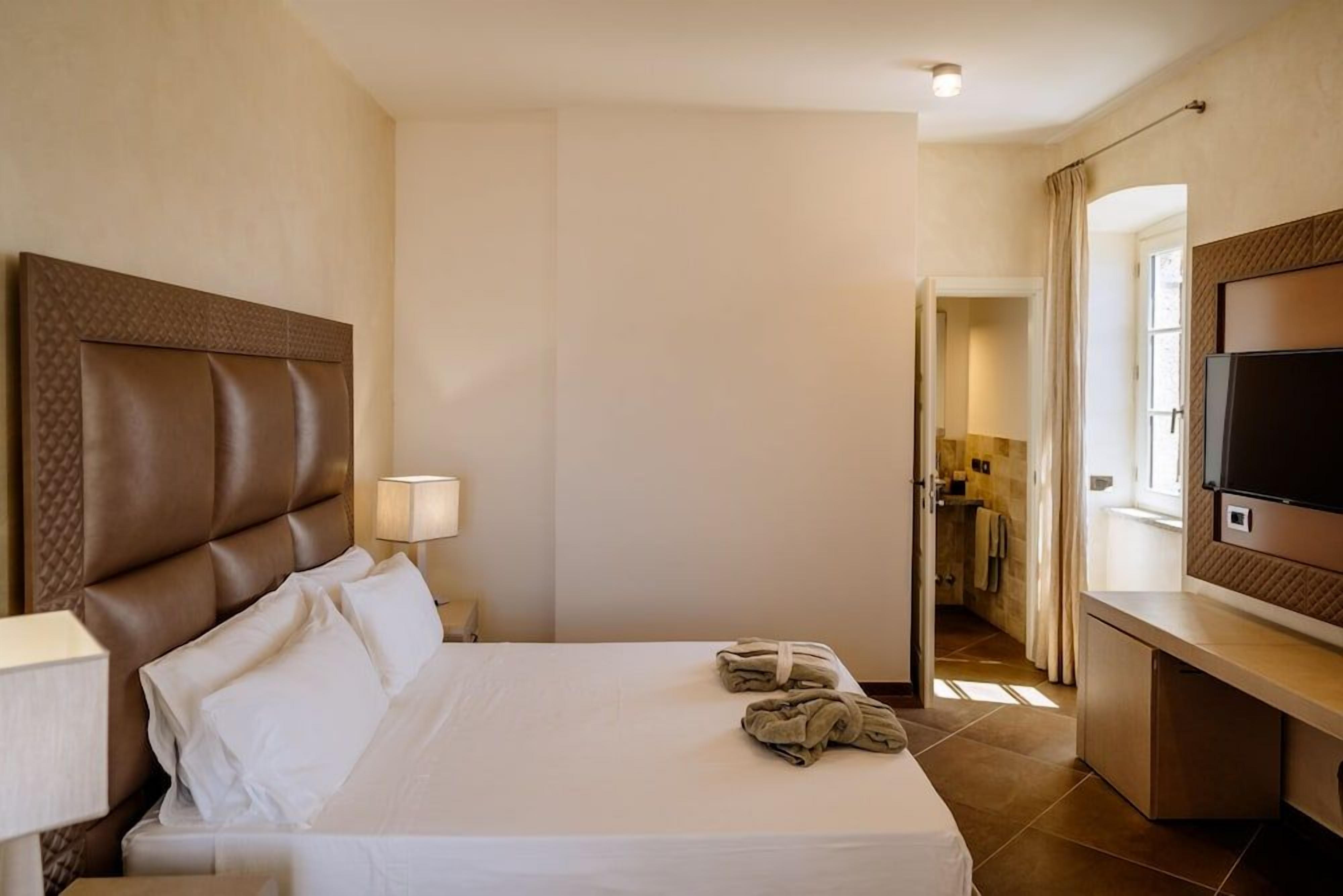 Une chambre d’hôtel avec un grand lit, une télévision et une salle de bain visible à travers une porte ouverte.