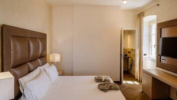 Une chambre d’hôtel avec un grand lit, une télévision et une salle de bain visible à travers une porte ouverte.