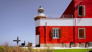Ein rot-weißes Gebäude mit Leuchtturm, Außenbereich und blauem Himmel.