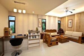 A modern living room with a sofa, a coffee table, a wooden side table, a bar area with a chair, and a bookshelf. - Li Wu Zuo Can B&B (Xiulin)
