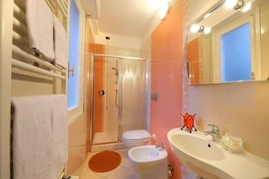 Un bagno completo con doccia, wc, bidet e lavandino.