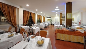 A dining area with tables set for meals, a buffet line, and a staircase leading to an upper level. - Arma (Taggia)