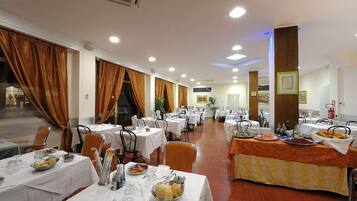 A dining area with multiple tables, chairs, and a buffet setup.