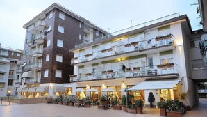 A multi-story hotel with outdoor seating and a covered patio area. - Arma (Taggia)