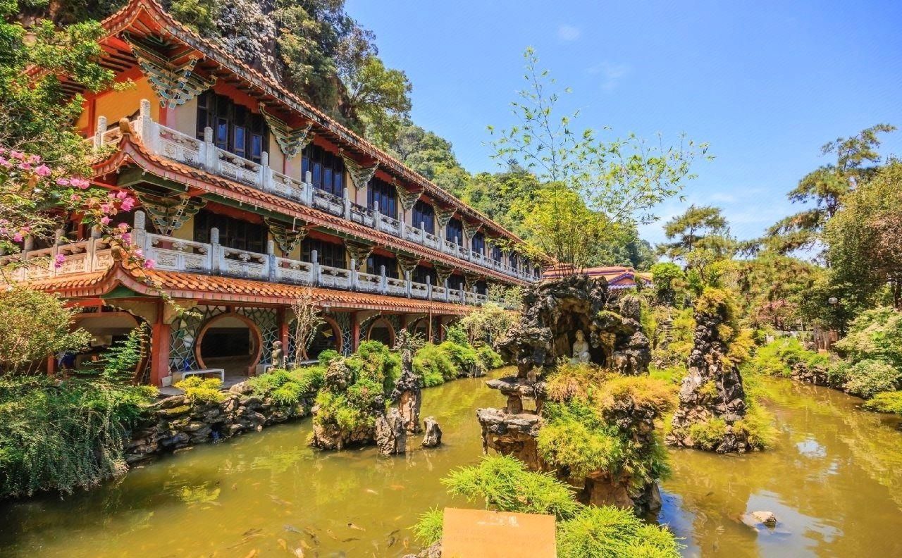 A traditional building with multiple balconies and a pond with rocks and plants.