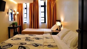 A hotel room with two beds, a television, a bedside table, and a window with curtains. - Silver Star Hotel (Brinchang)