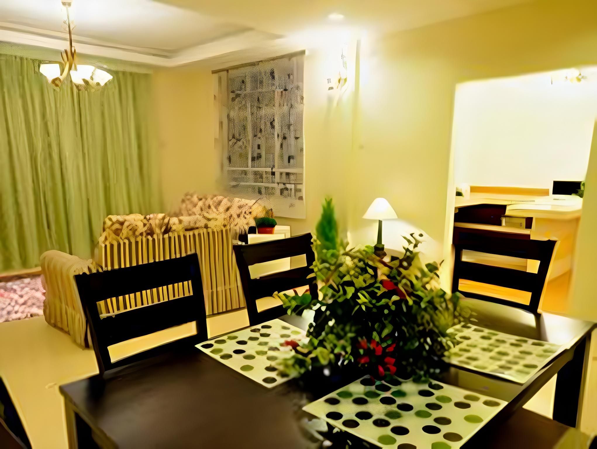 A dining area with a table set for four, chairs, a vase with flowers, and a window with a view of buildings.