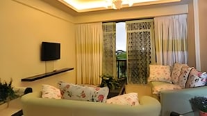 A living room with a sofa, a TV mounted on the wall, and a ceiling light fixture. - Silver Star Hotel (Brinchang)