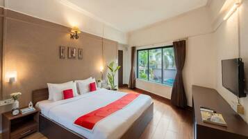 A hotel room with a large bed, bedside tables, a TV, and a window with curtains.