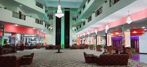 A hotel lobby with a central staircase, multiple seating areas, and a high ceiling with chandeliers. - Howard Johnson Ooty India (Ootacamund)