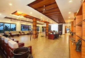 A spacious lobby with a reception desk, seating area, and large windows. - Arayal Resorts: A Unit of Sharoy Resort (Vythiri)
