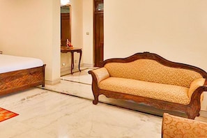 A hotel room with a bed, a sofa, and a small table. - Club Mahindra Bharatpur (Bharatpur)