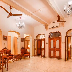 A spacious room with a ceiling fan, a chandelier, and ornate wooden doors. - Club Mahindra Bharatpur (Bharatpur)