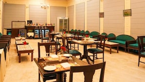 A hotel dining room with multiple tables, chairs, and a bar area. - Club Mahindra Bharatpur (Bharatpur)