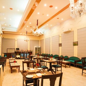 Une salle à manger d’hôtel avec de nombreuses tables, des chaises et un coin bar.