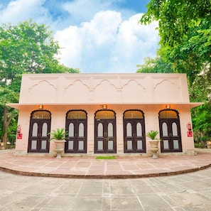 A building with a symmetrical facade, multiple dark-colored doors, and a central entrance. - Club Mahindra Bharatpur (Bharatpur)