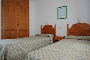 Quarto com duas camas de madeira, um guarda-roupa e um quadro pendurado na parede.