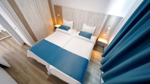 A double bed with a blue accent, two bedside tables with lamps, and a wooden headboard. - Apartamentos Blue Star (Mogan)
