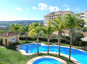A swimming pool surrounded by palm trees and a view of a mountainous landscape. - 3 Bed Apartment - Sleeps 6 - Pool - Parking - Golf (Mijas)