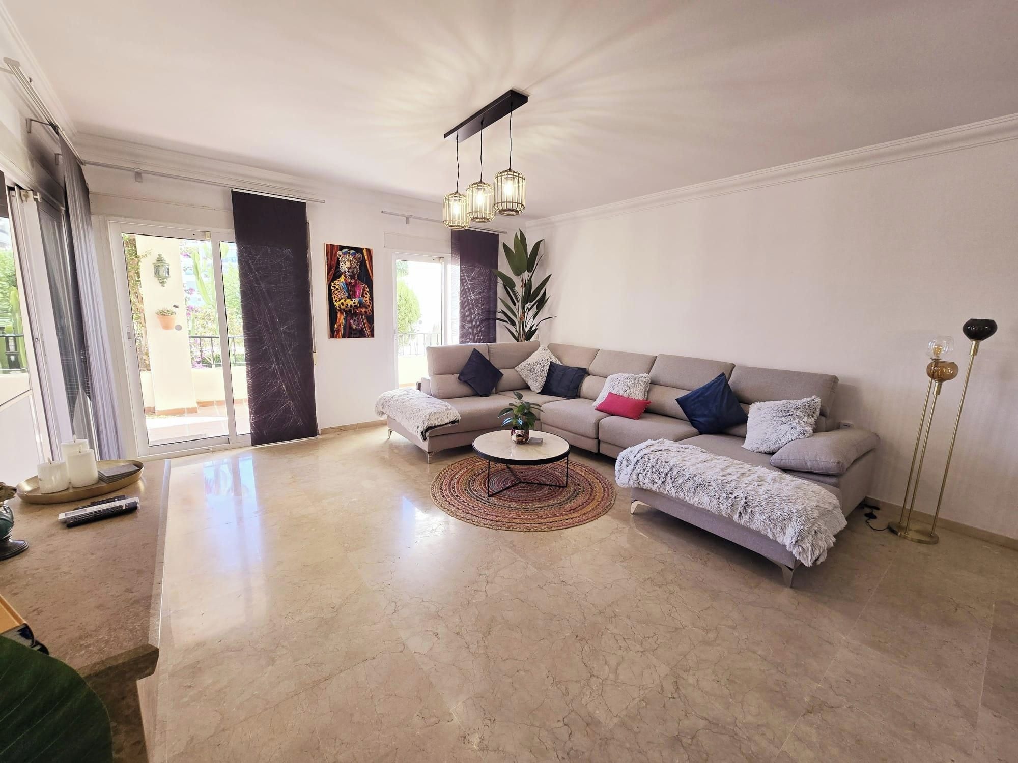 Un salon spacieux avec un canapé beige, une table basse et une grande fenêtre.