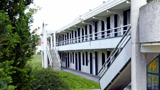 Un edificio con un espacio exterior techado, que incluye una escalera y mesas de picnic.