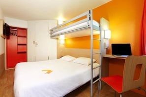 Habitación de hotel con una cama litera, un escritorio con computadora, una silla y un televisor.