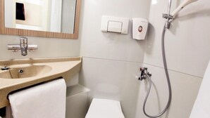 Un baño con lavamanos, espejo, toalla, inodoro y ducha con cabezal de ducha manual.