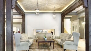 A spacious living room with a brick-patterned floor, two armchairs, a coffee table, and a fireplace. - Aubrecht Country Resort And Spa (Przechlewo)