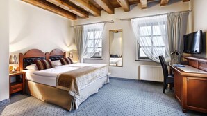 A hotel room with a bed, a desk, a chair, a television, and a window with curtains. - Aubrecht Country Resort And Spa (Przechlewo)