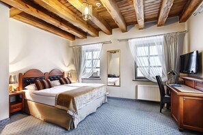 A hotel room with a bed, a desk, a chair, a television, and a window with curtains. - Aubrecht Country Resort And Spa (Przechlewo)