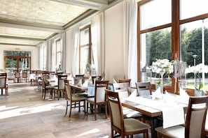 A spacious indoor dining area with multiple tables and chairs, large windows, and a view of greenery outside. - Aubrecht Country Resort And Spa (Przechlewo)