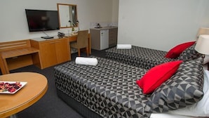A hotel room with two beds, a desk, a television, and a small kitchenette. - Grapevine Motel (Denman)