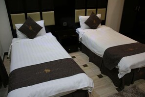 Two single beds with white linens and dark headboards, a small bedside table, and a dark-colored rug on the floor. - Dorar Darea Hotel Apartments Al Malqa 2 (Riyadh)