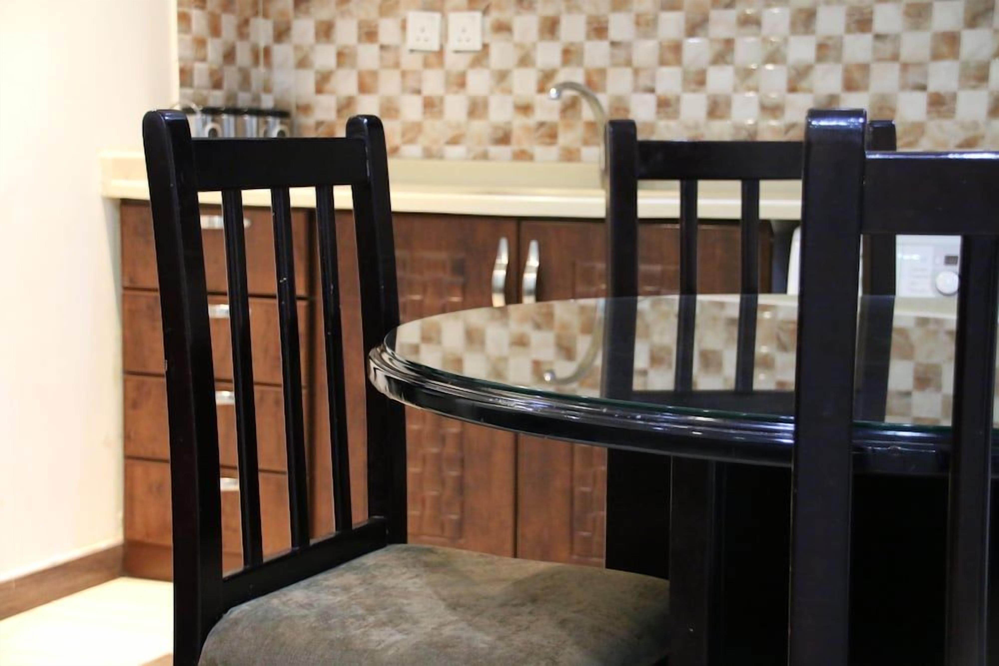 Un comedor con una mesa de vidrio y dos sillas negras.